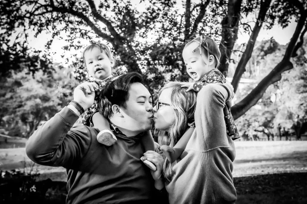 BW family portrait with parents holding twin babies on shoulders