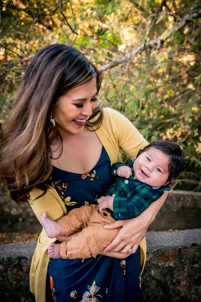 A beautiful mother smiles at her laughing baby in an outdoor family portrait by photographer Shelly Rivoli