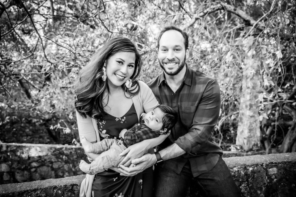 Black and white outdoor portrait of parents with newborn baby