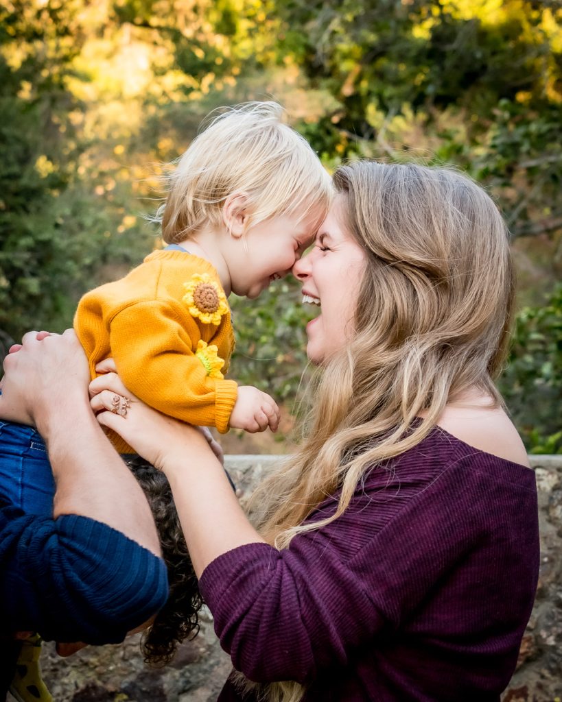 Lifestyle outdoor family portrait of toddler laughing with mom in park