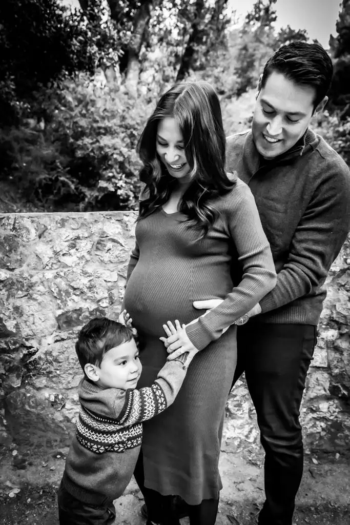 Family maternity photo with young child's hands on mom's pregnant belly
