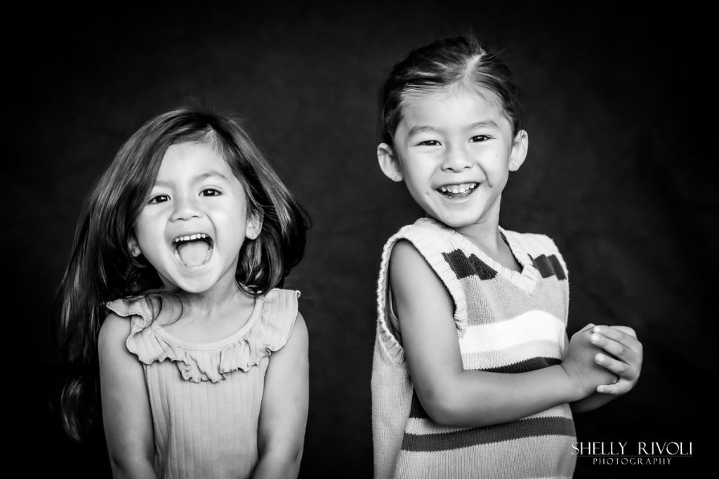 funny BW portrait of brother and sister being silly by children's photographer Shelly Rivoli